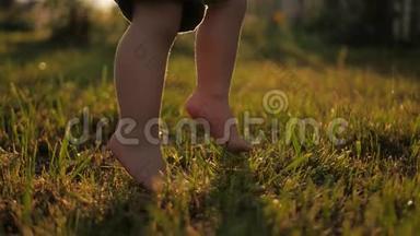 小<strong>宝宝</strong>学会<strong>走路</strong>.. 动作缓慢。 孩子们在日落时在绿草上做第一步。 快关门
